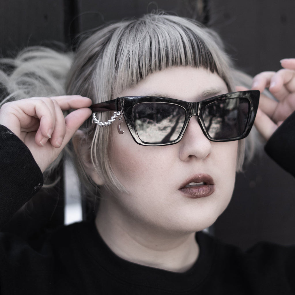 Person wearing large sunglasses with a dark background