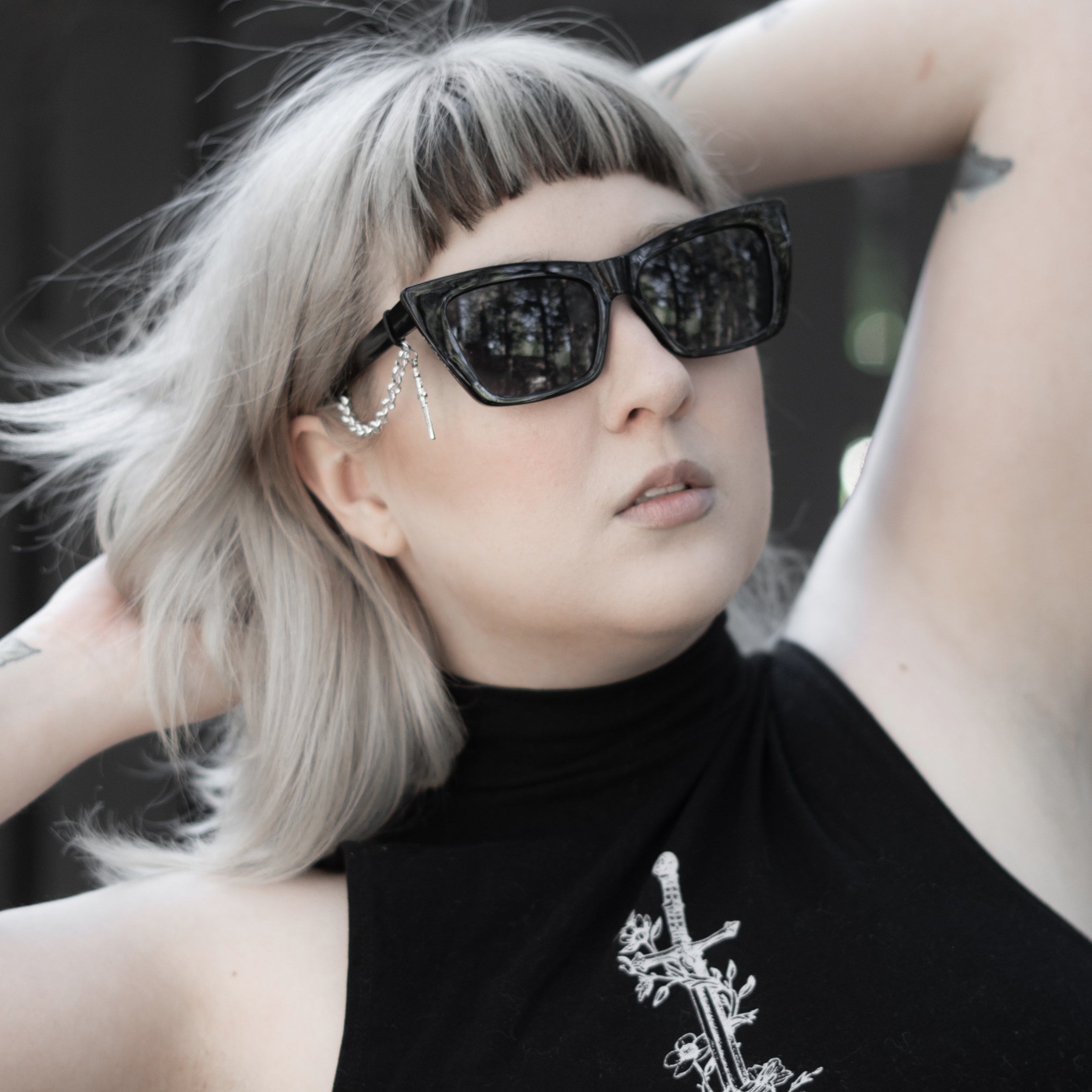 Person wearing black sunglasses and a black turtleneck with a white design.