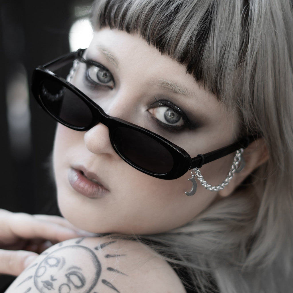 Person with sunglasses and a tattoo on shoulder against a blurred background