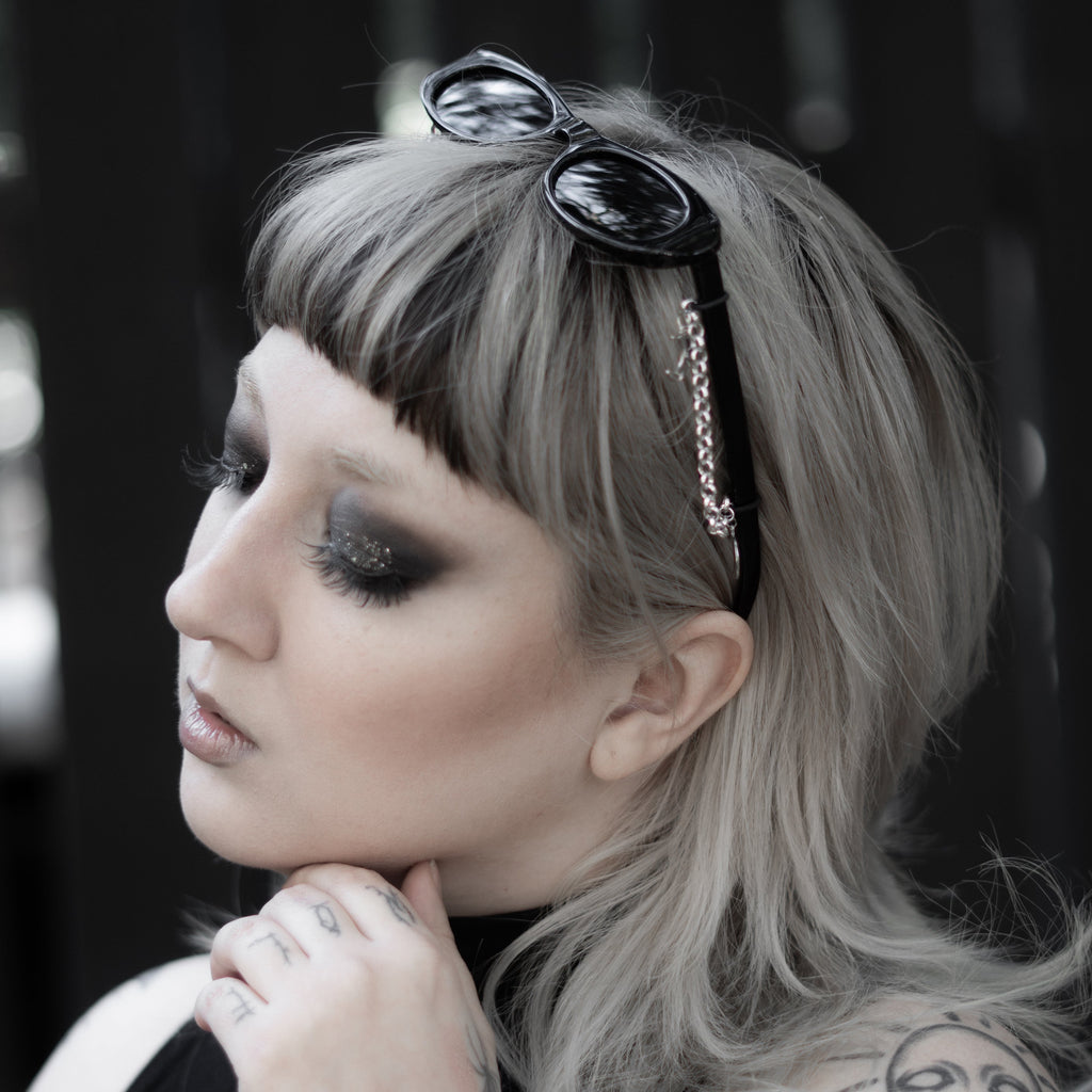 Woman with tattoos and sunglasses on her head against a blurred background