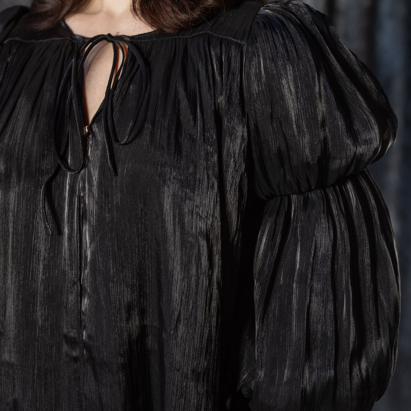 Woman wearing a black dress with puffed sleeves against a dark background