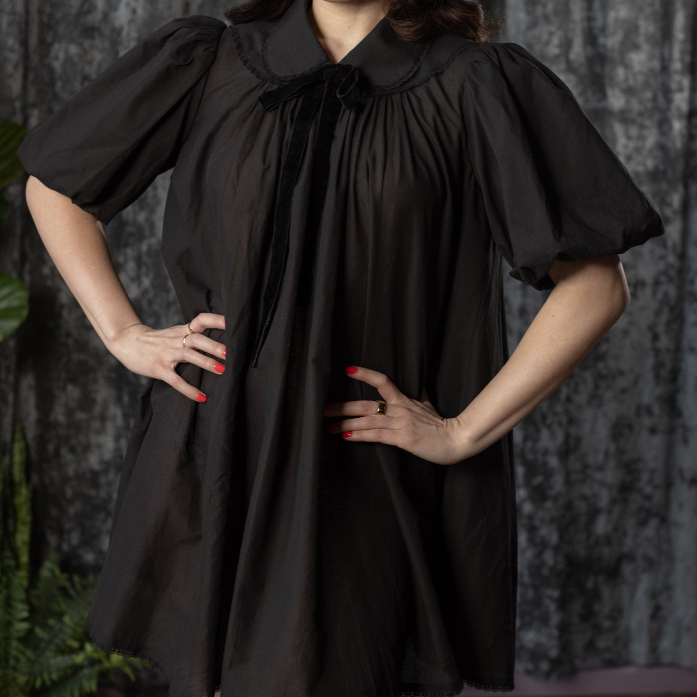 Woman wearing a black dress with a collar against a dark background