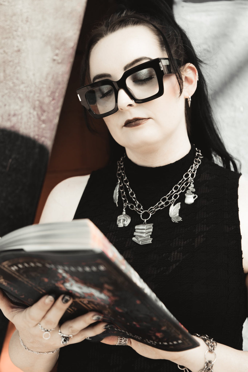 Person wearing glasses and reading a book with a blurred background
