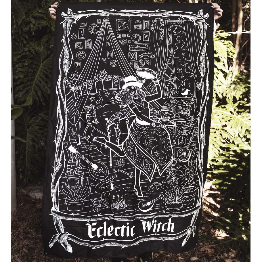 Person holding a black and white 'Eclectic Witch' tapestry with intricate designs and text.