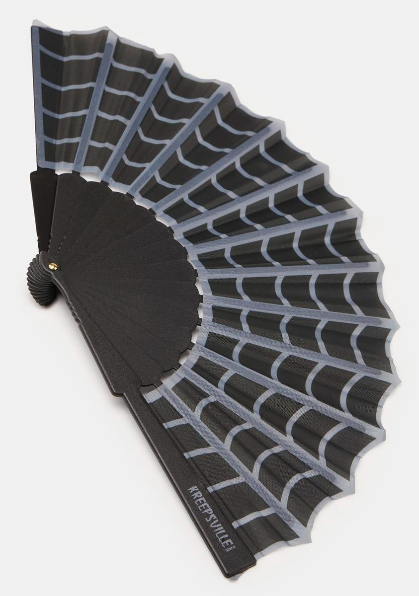 A folding hand fan with a black plastic frame and translucent gray ribs, shown open against a light gray background. The brand name 'KREESEYULE!' is printed in white on the lower edge of the black handle.