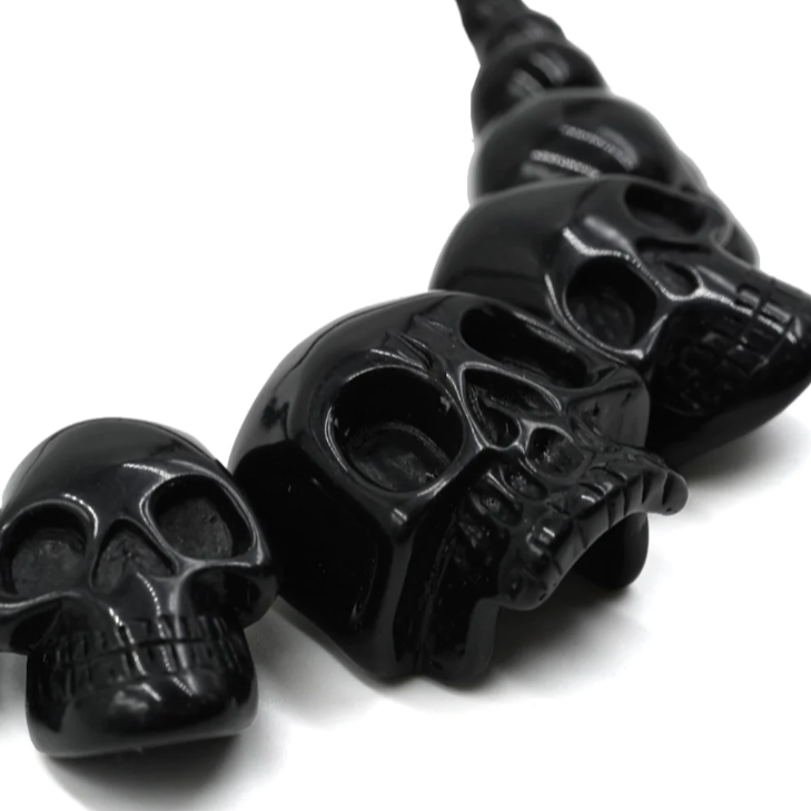 A glossy black skull-shaped spiral charm or bead strand shown on a plain white background.