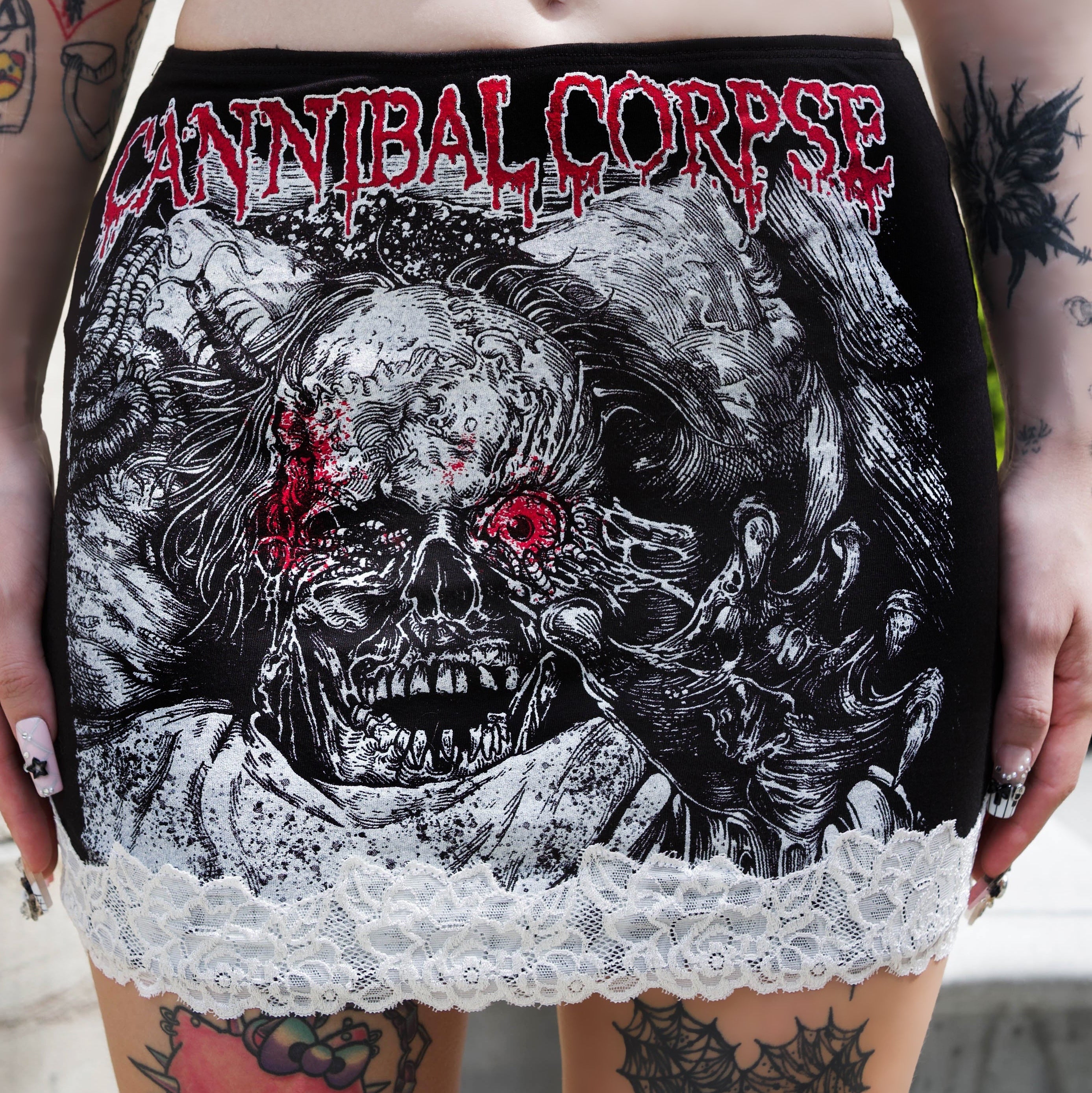 Person wearing a black and red 'Cannibal Corpse' skirt with a skull design.