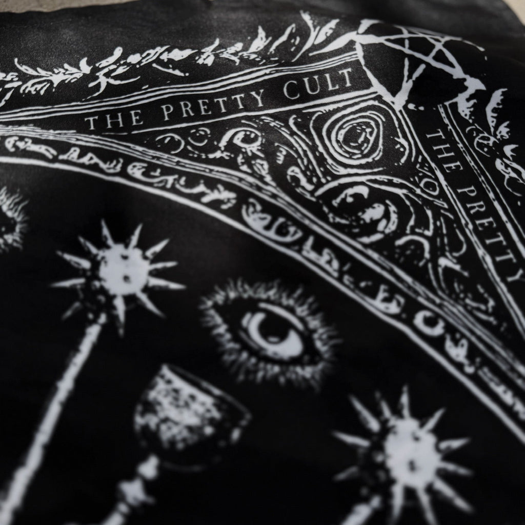 Black scarf with white designs and text on a textured surface