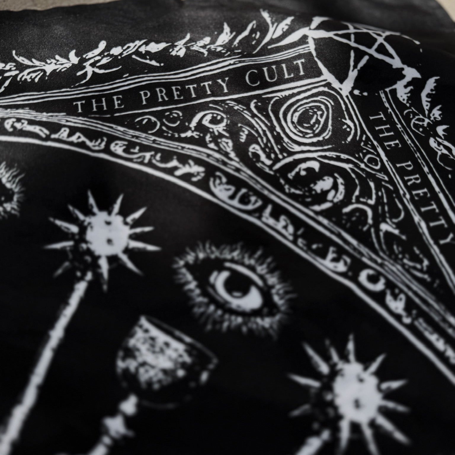 Black scarf with white designs and text on a textured surface