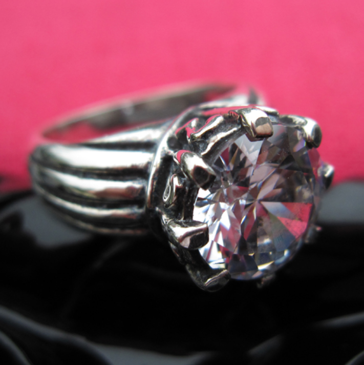 Silver ring with a large diamond on a pink background