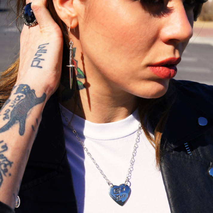 Close-up of a person wearing earrings and a necklace with a blue pendant.