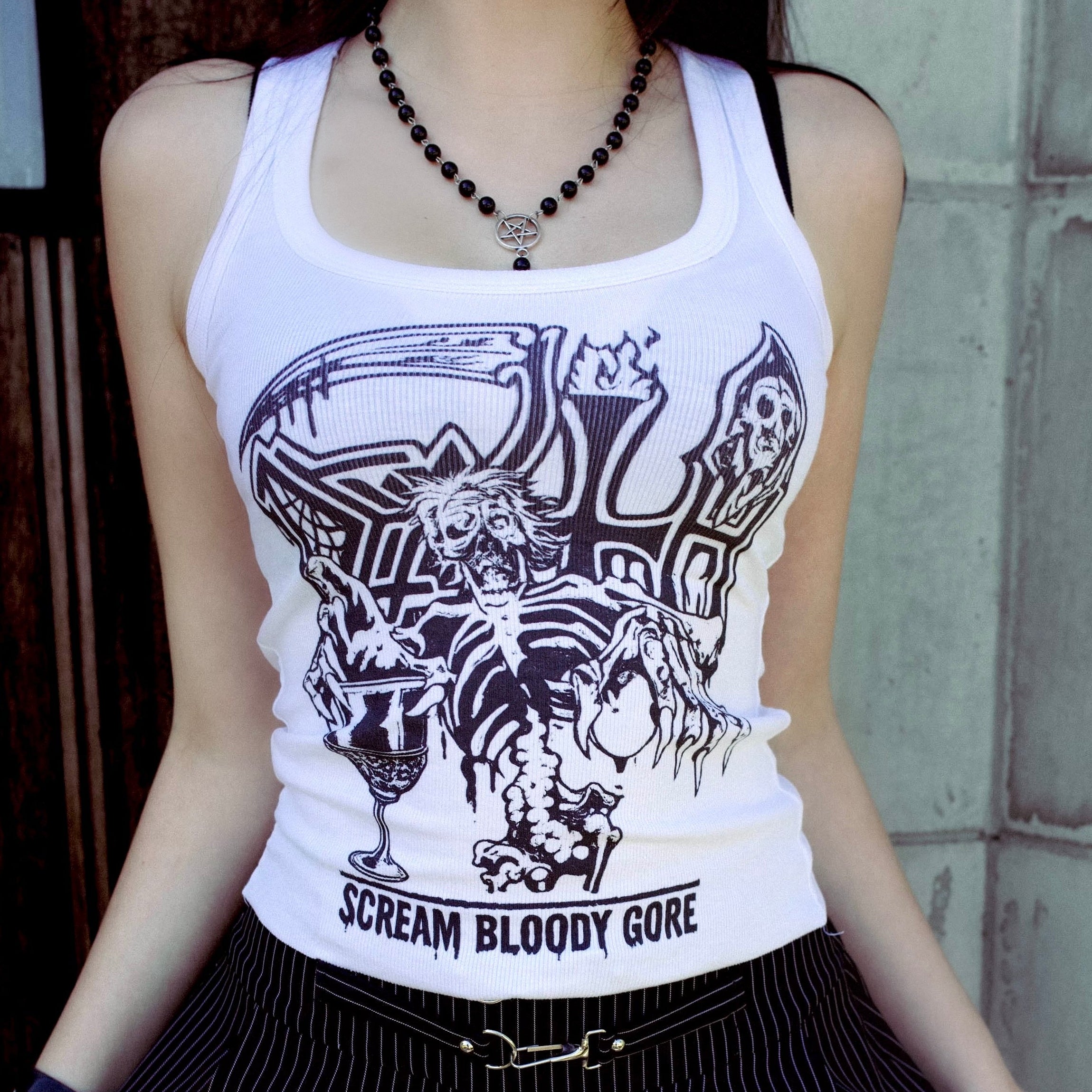 Person wearing a white tank top with graphic design and text, black skirt, and lace stockings.
