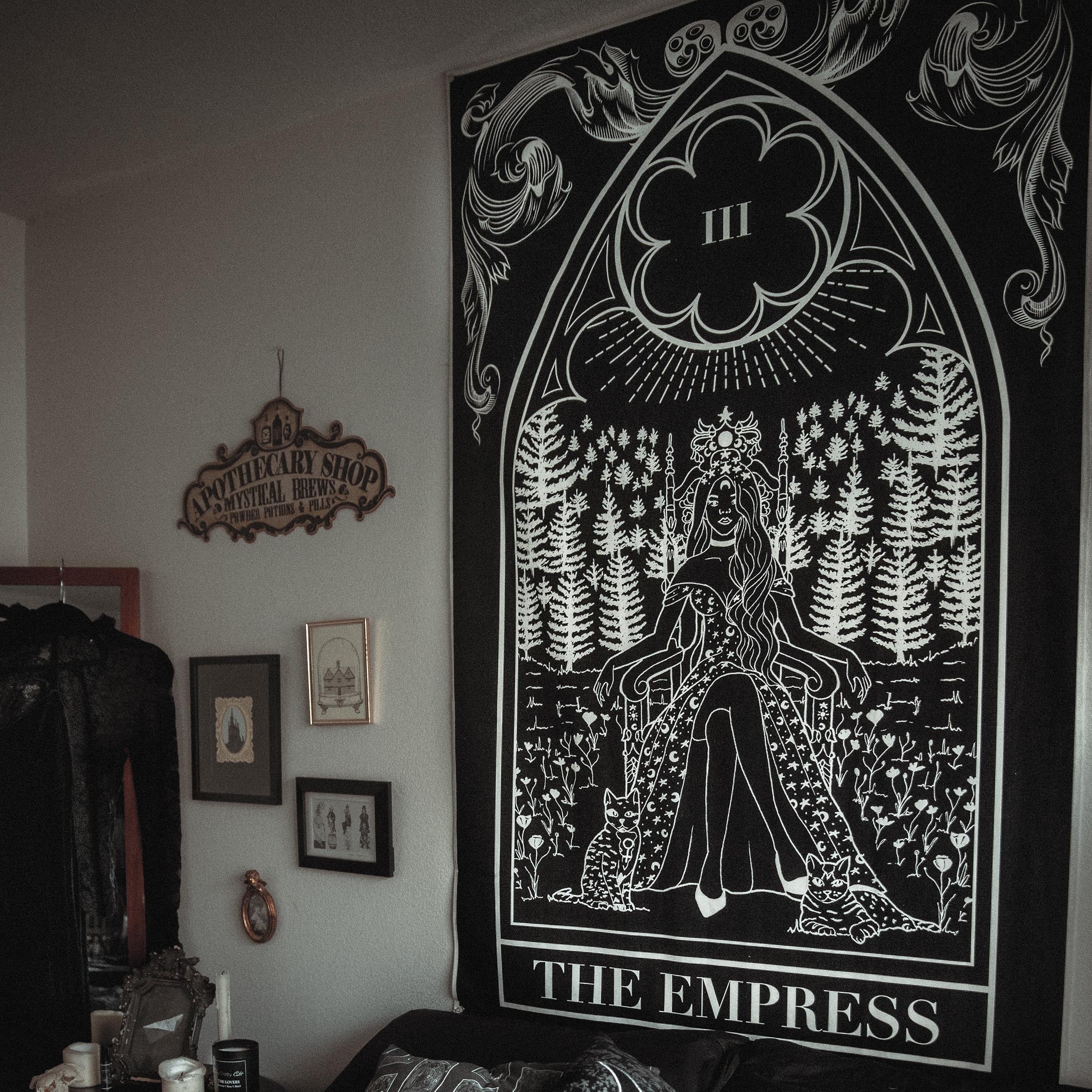 Tapestry titled 'The Empress' hanging on a wall above a couch with decorative pillows.