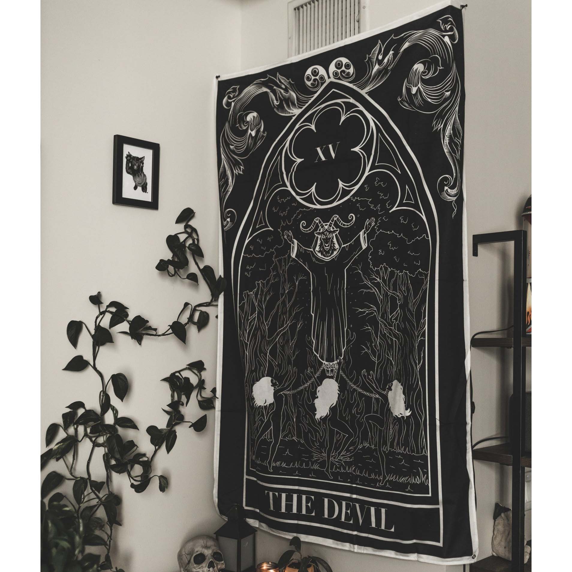 Black and white tapestry with 'The Devil' design hanging on a wall.