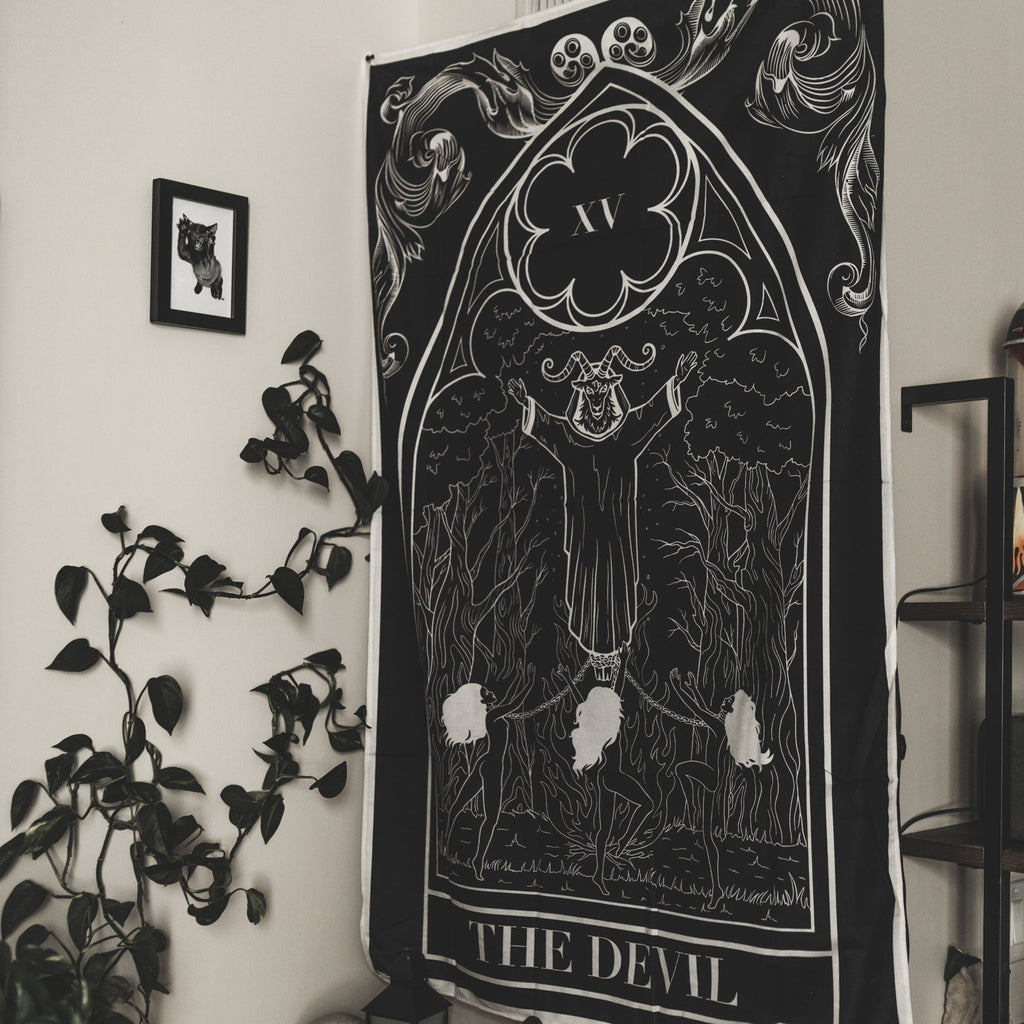 Decorative tapestry with 'The Devil' design hanging on a wall in a room.