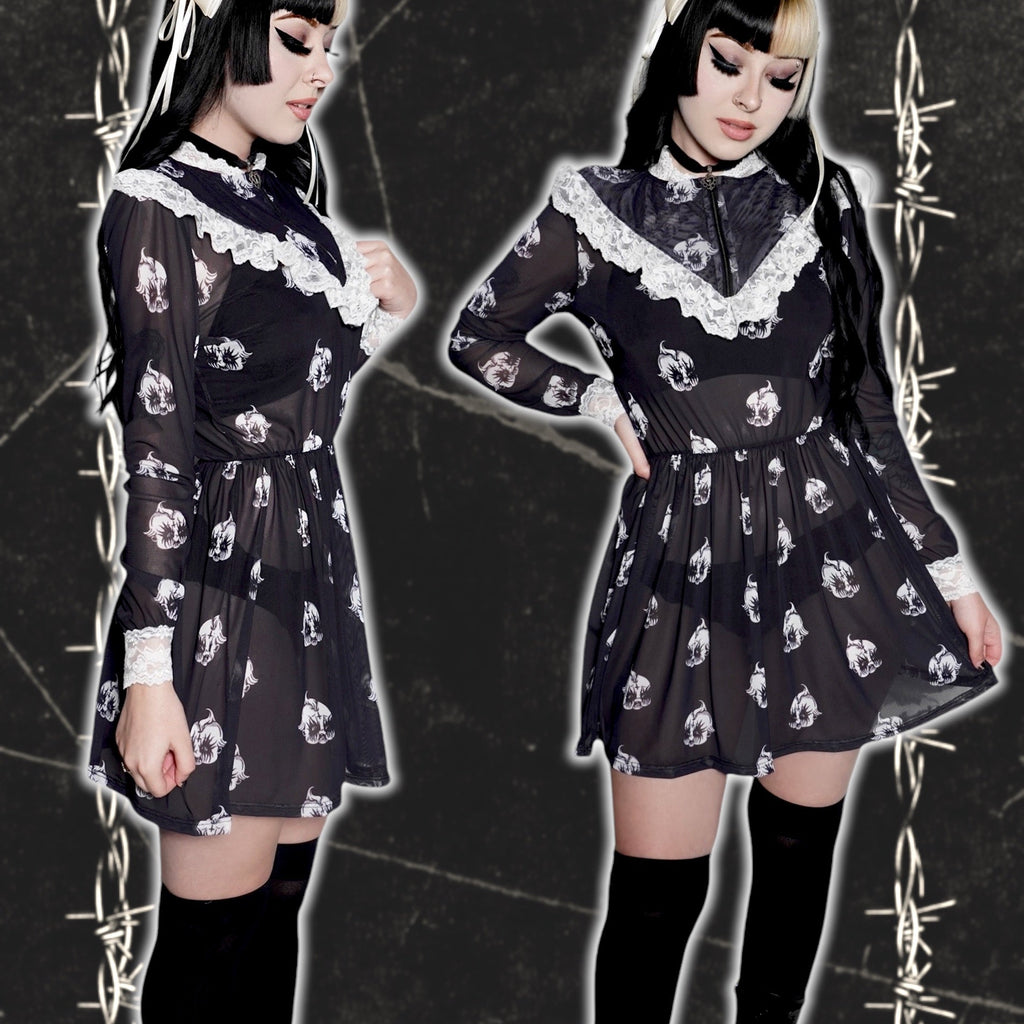Person wearing a black dress with white patterns on a dark background with barbed wire.