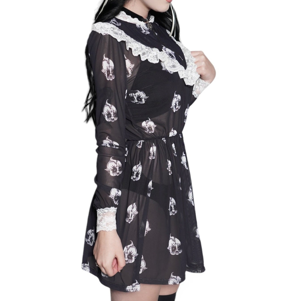 Person wearing a black dress with white floral patterns and knee-high black boots on a white background