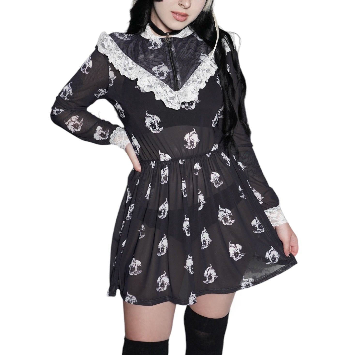 Person wearing a black dress with white patterns and black knee-high boots on a white background