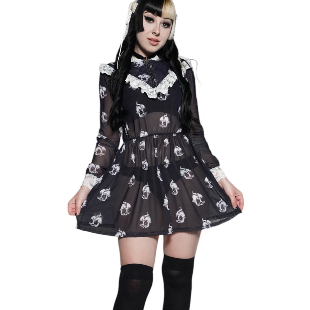 Person wearing a black dress with white patterns and black knee-high boots on a white background