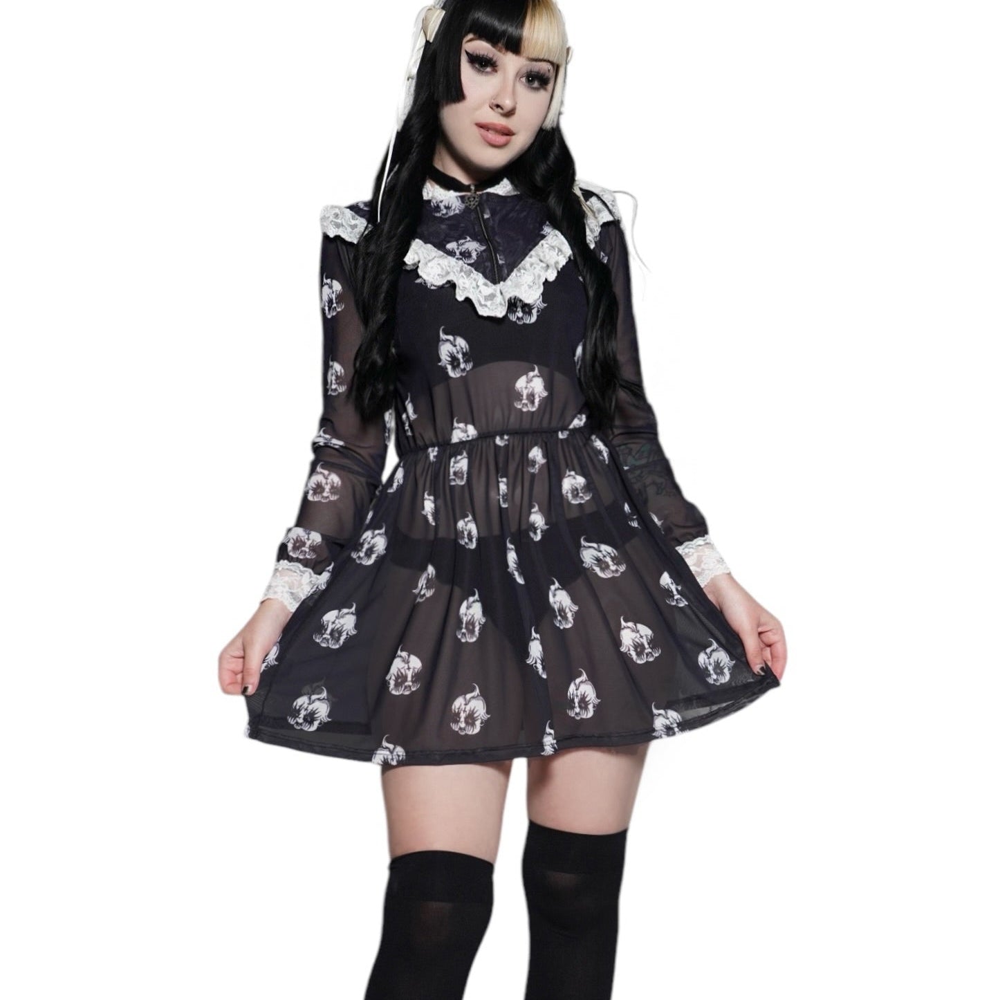 Person wearing a black dress with white patterns and black knee-high boots on a white background