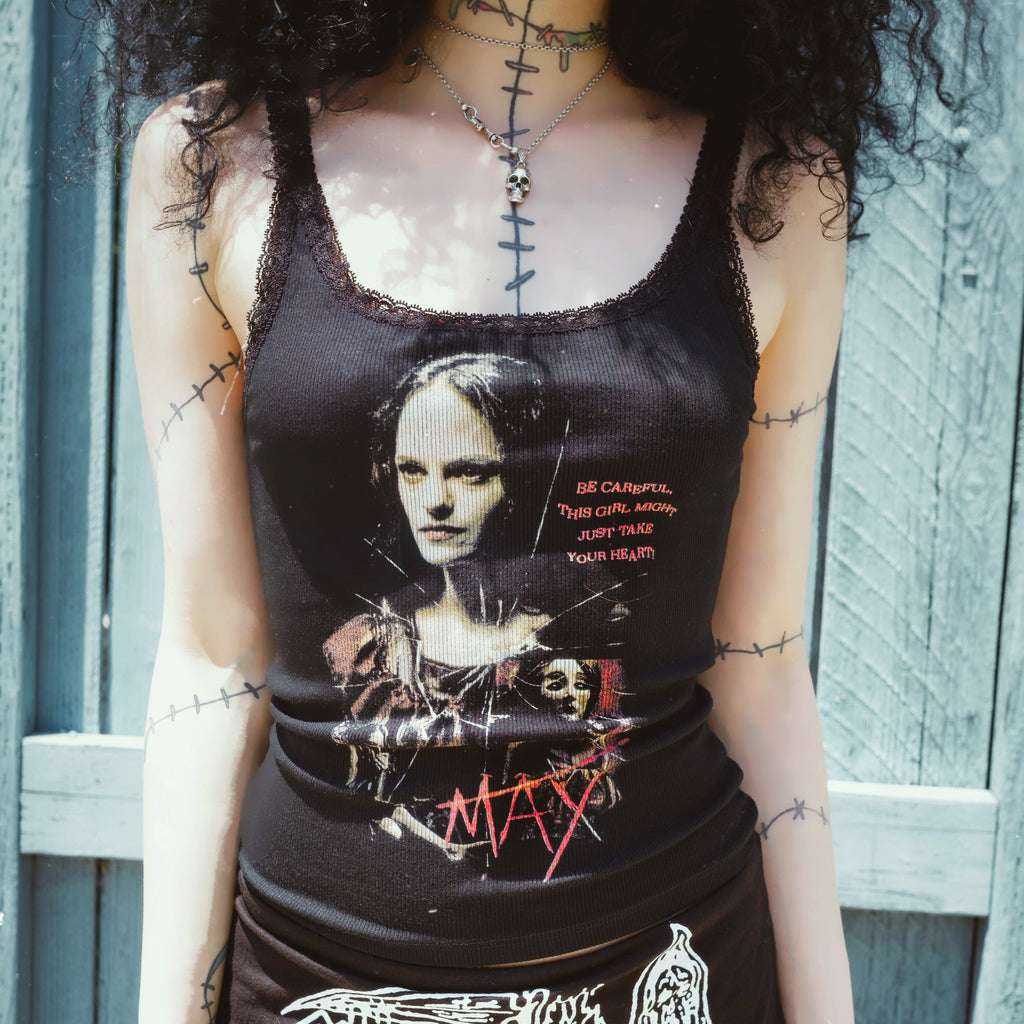 Person wearing a black tank top with graphic design against a wooden fence background