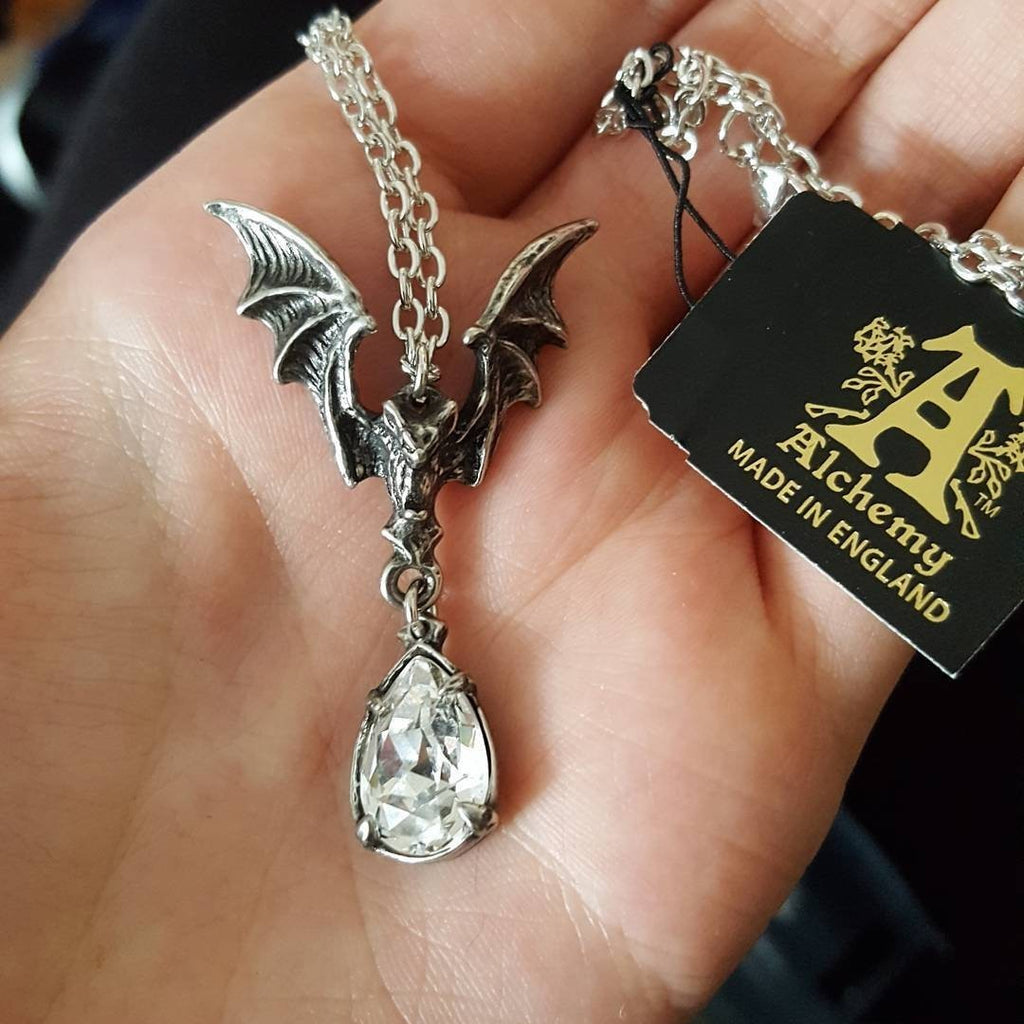 Silver bat pendant necklace with a clear gemstone on a hand, Alchemy England tag visible.