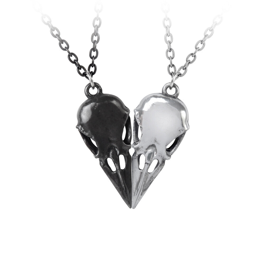 Two bird skull pendants, one black and one silver, on a white background.