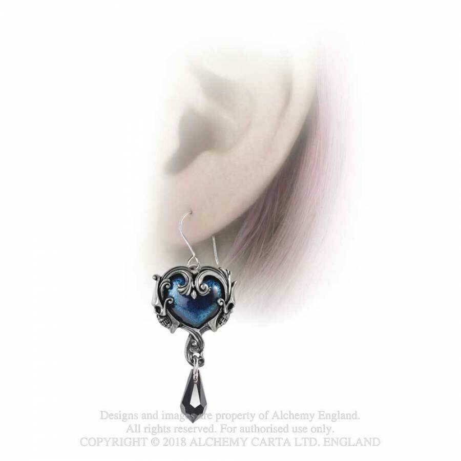 Heart-shaped earring with blue design worn on an ear against a white background