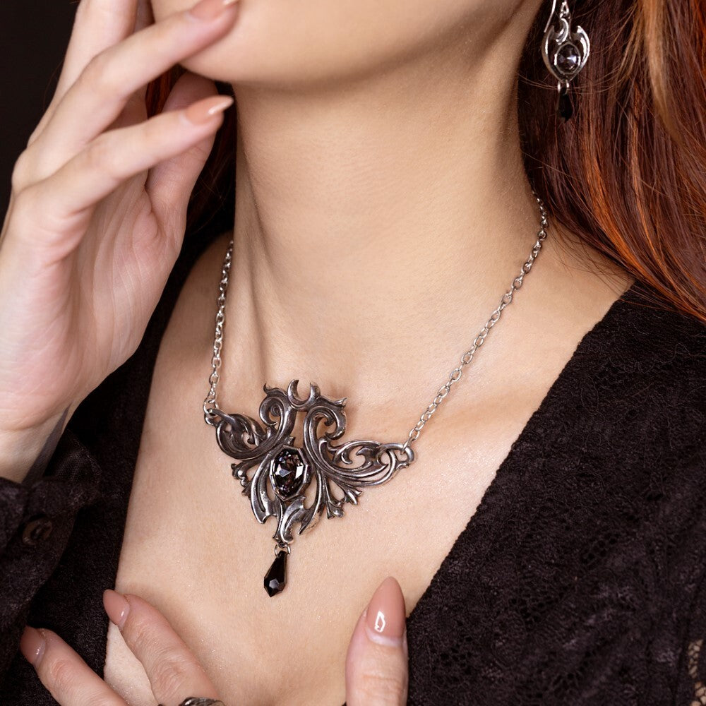 Close-up of a woman wearing an ornate silver necklace with a dark pendant.
