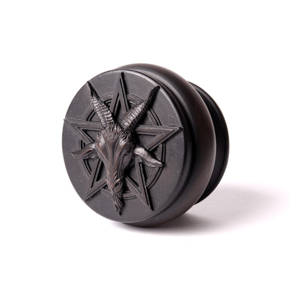 Black circular object with goat head and pentagram design on a white background