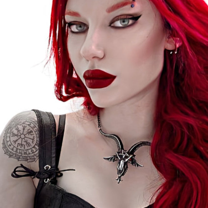 Person with red hair and red lipstick wearing a black necklace with a demon pendant.