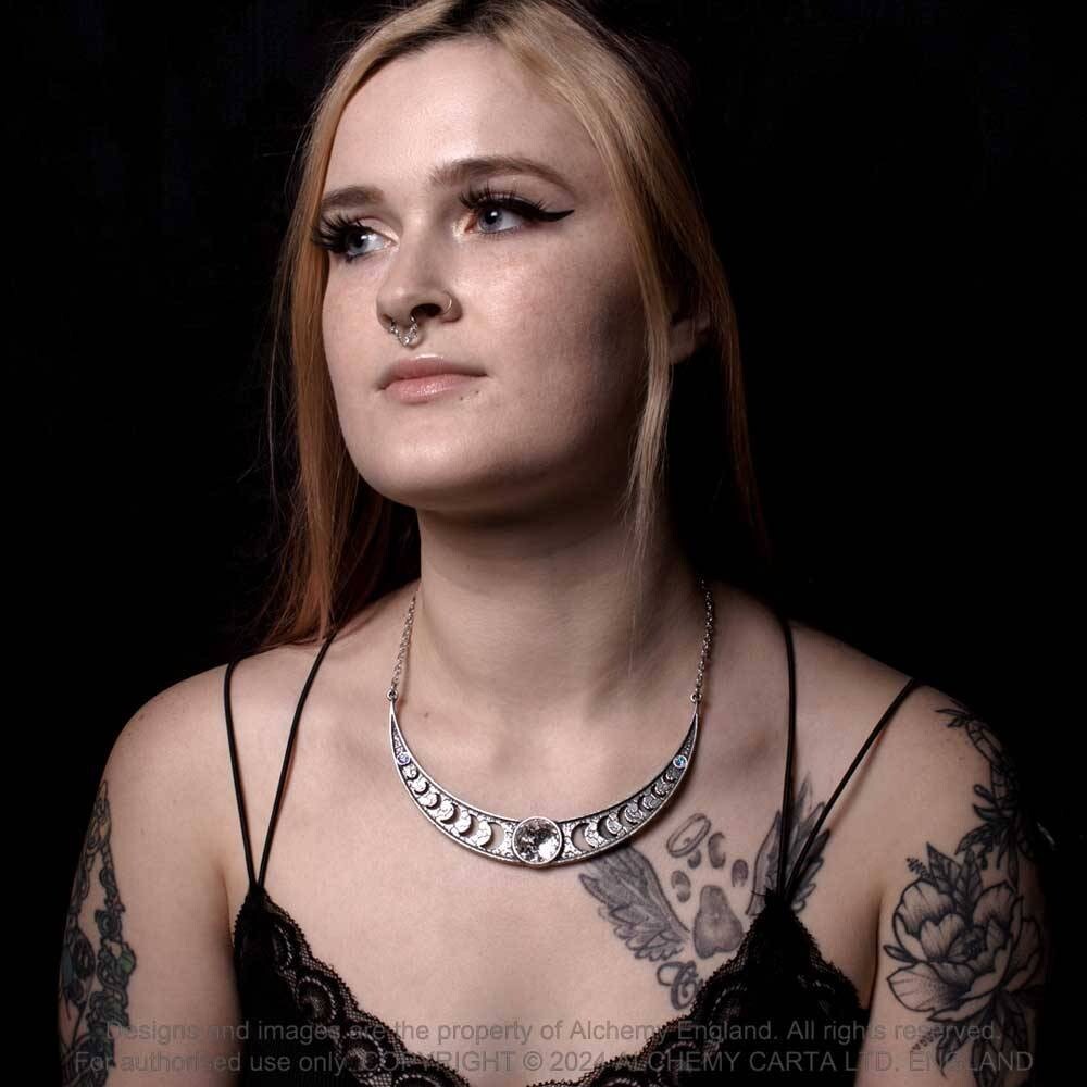 Woman with tattoos and a necklace against a black background