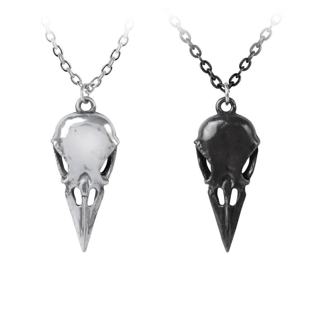 Two bird skull pendants on chains against a white background