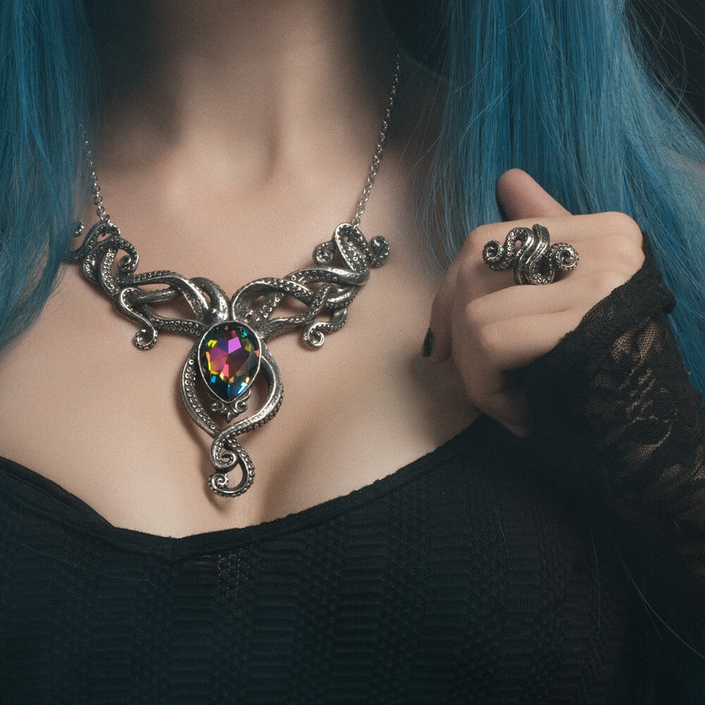 Person wearing a detailed necklace with a colorful gemstone and matching ring.