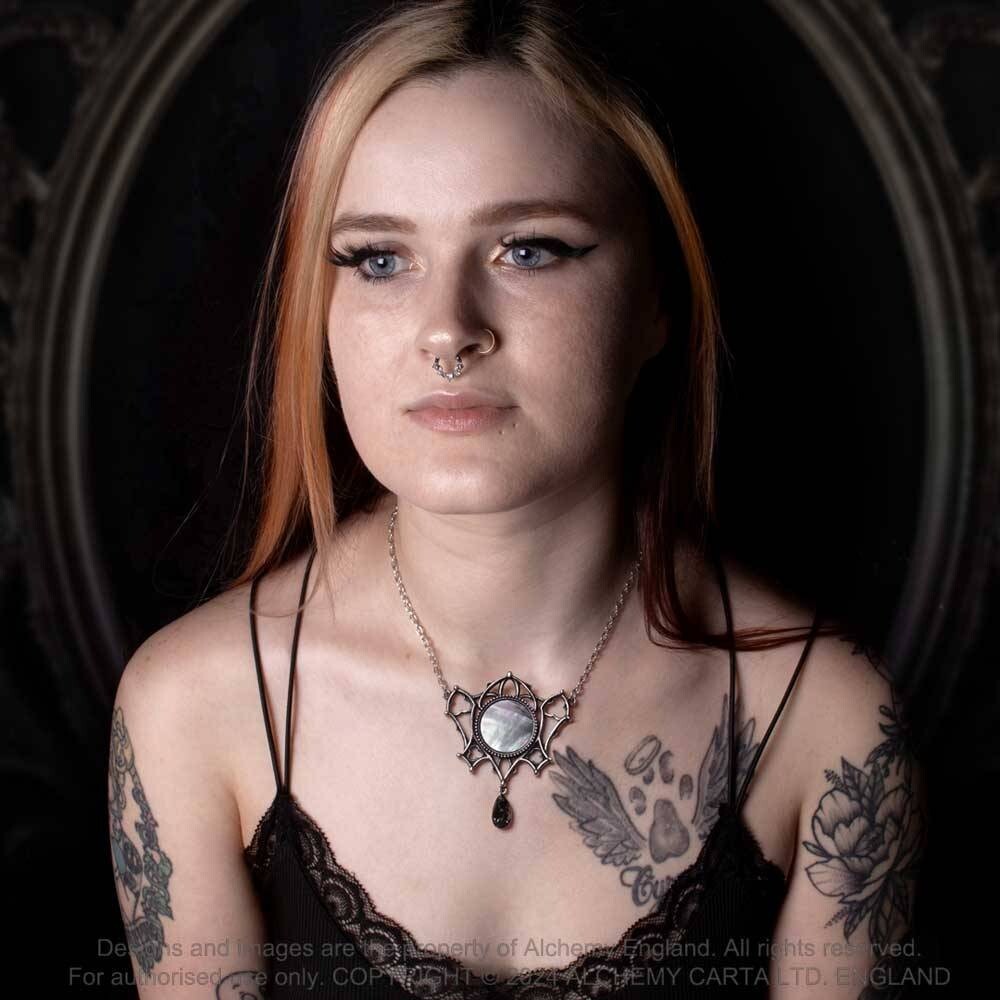 Woman with tattoos and a necklace in a dark setting