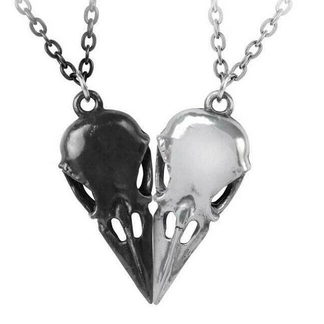 Two bird skull necklaces, one black and one silver, on a white background.