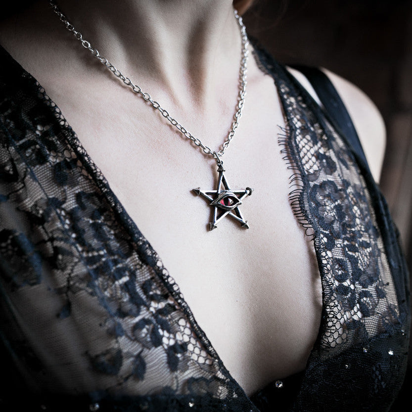 Person wearing a black lace garment with a star-shaped pendant necklace, Alchemy England logo visible.