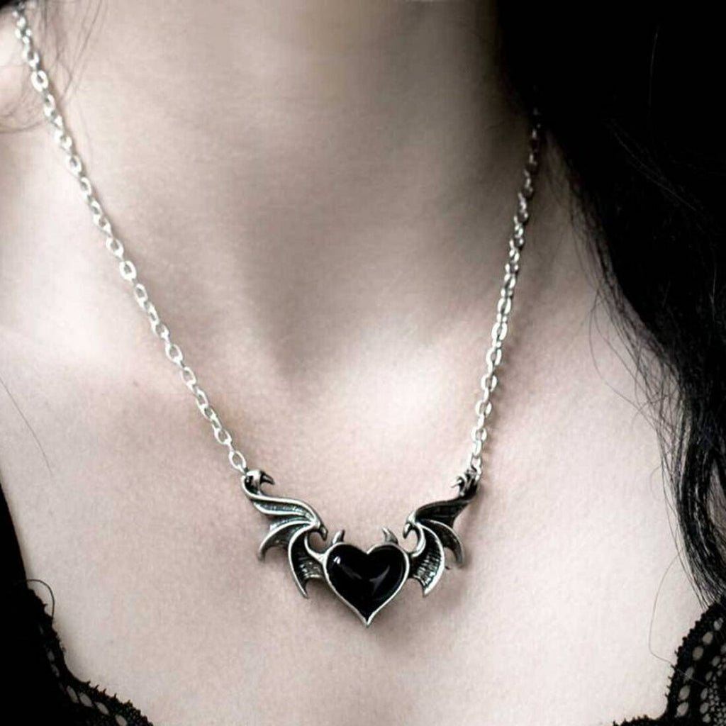 Necklace with a black heart and wings pendant on a person's neck.