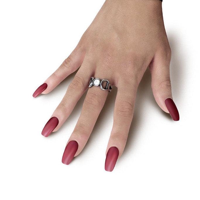 Hand wearing a bracelet and ring with red nail polish on a white background