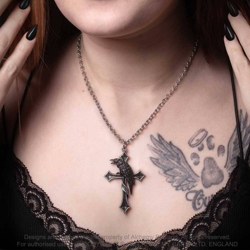 Close-up of a person wearing a necklace with a cross pendant, showing tattoos on the chest.