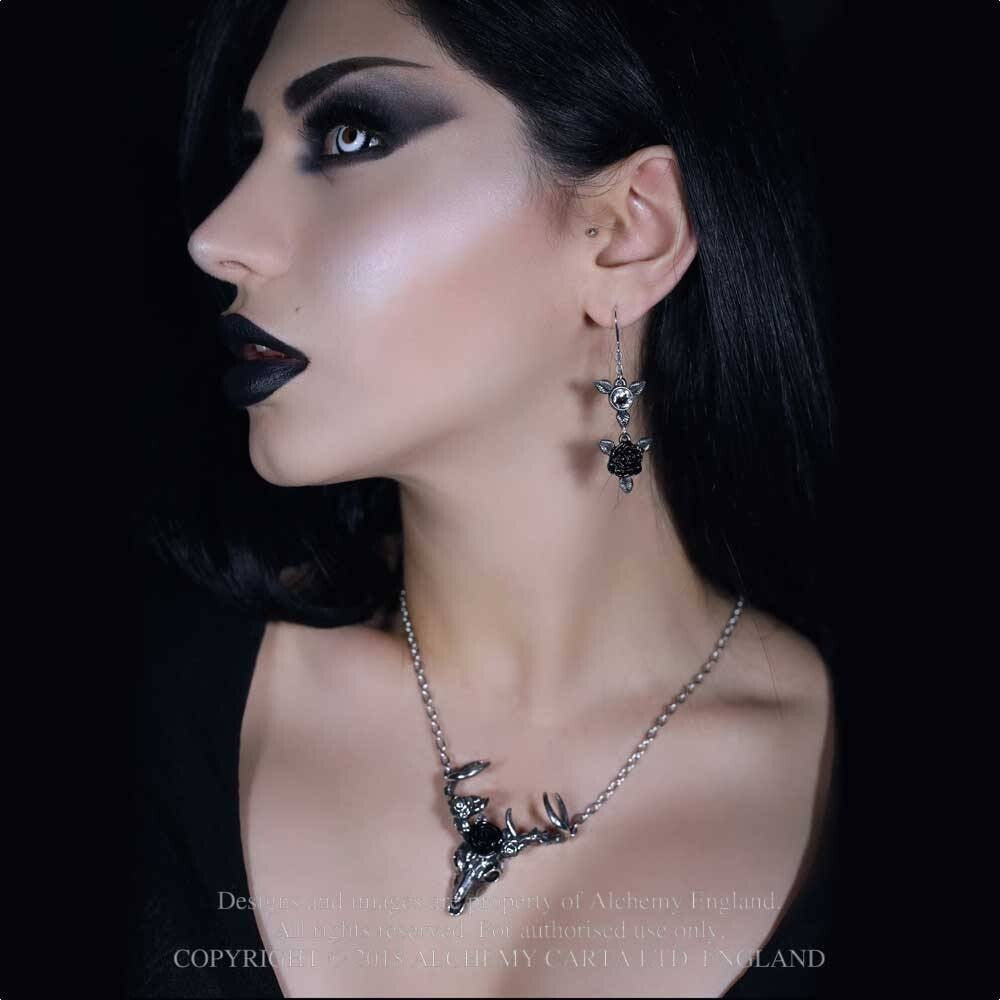 Woman wearing a black necklace and earrings with a dark background