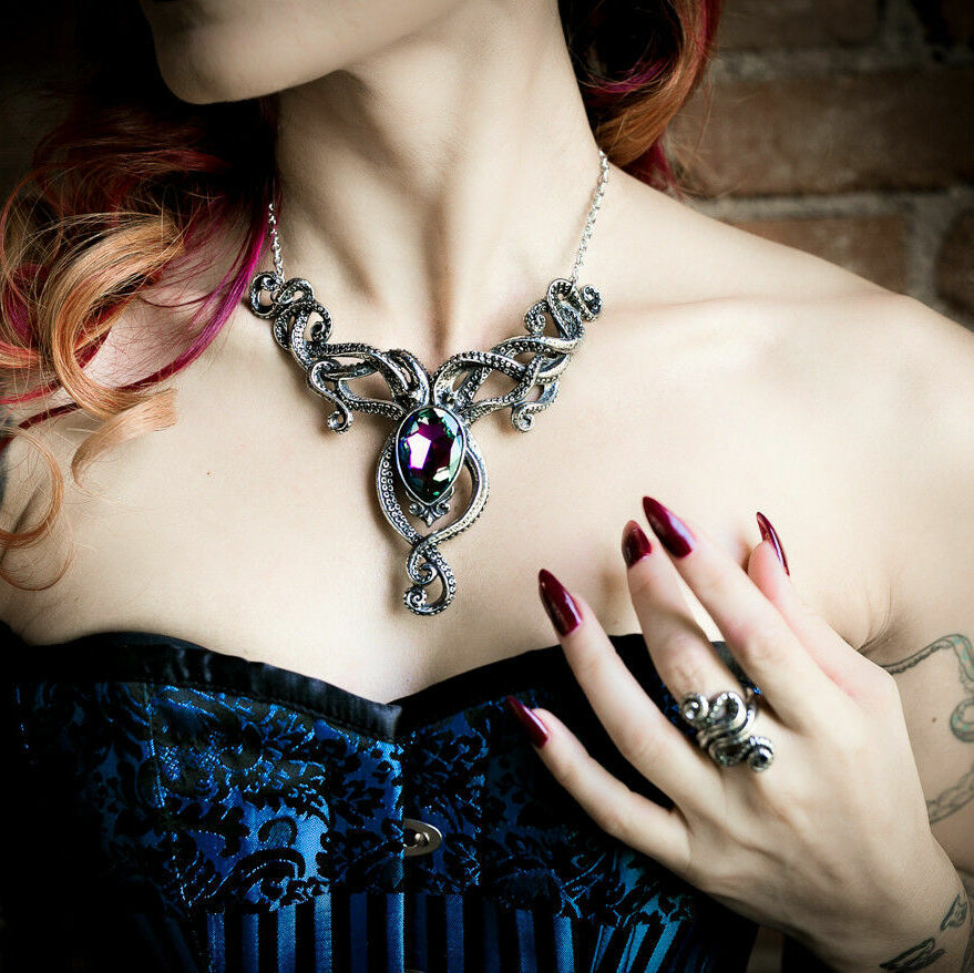 Woman wearing a detailed necklace with a large gemstone against a dark background