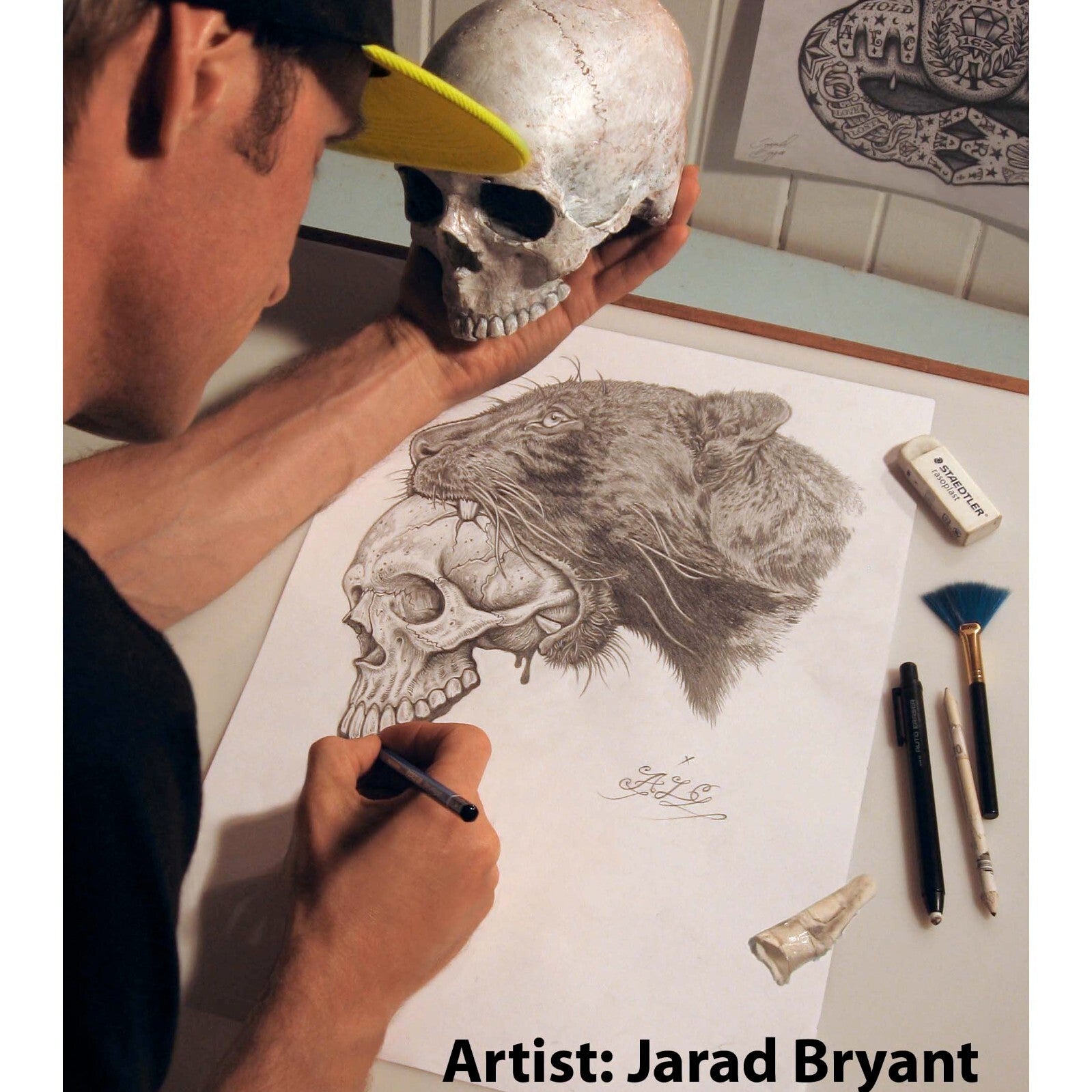 Person holding a skull next to a drawing of a skull and panther, with 'Artist: Jarad Bryant' text.