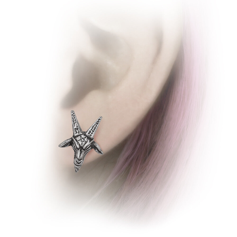Silver goat head earring worn on an ear with a blurred background