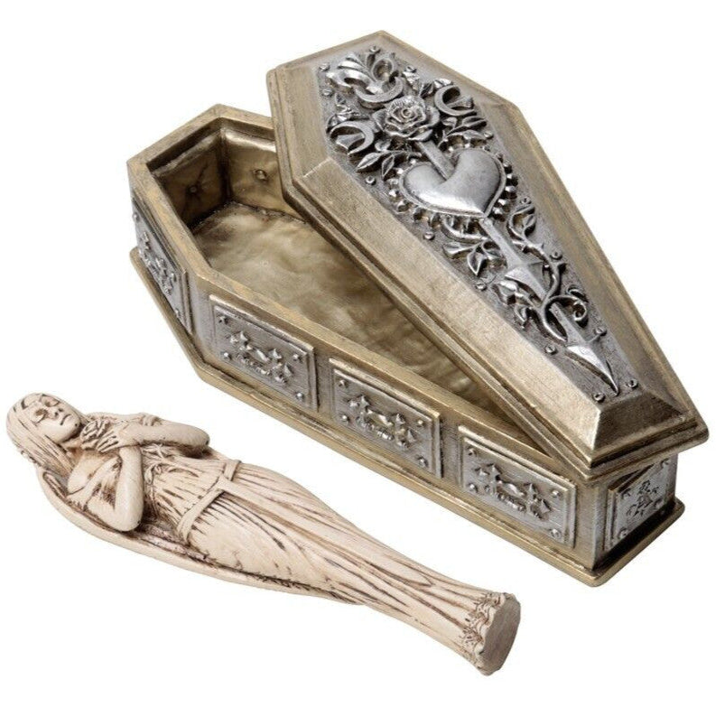 Decorative coffin-shaped box with ornate designs and a small figurine of a woman inside on a white background.