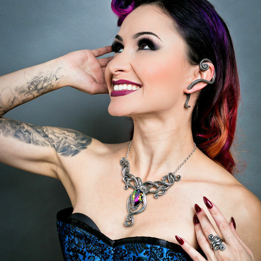 Woman with stylized hair and makeup wearing a blue corset against a gray background