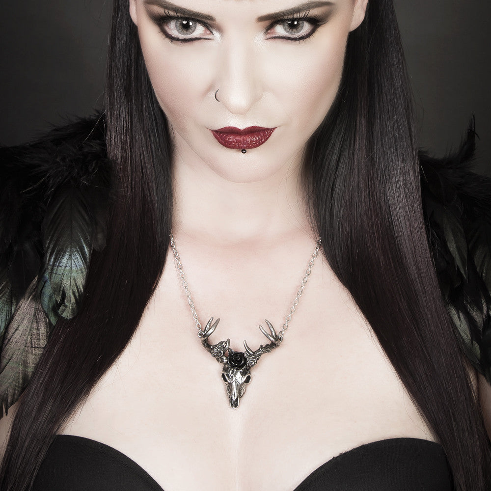 Woman wearing a necklace with a black and silver design against a dark background
