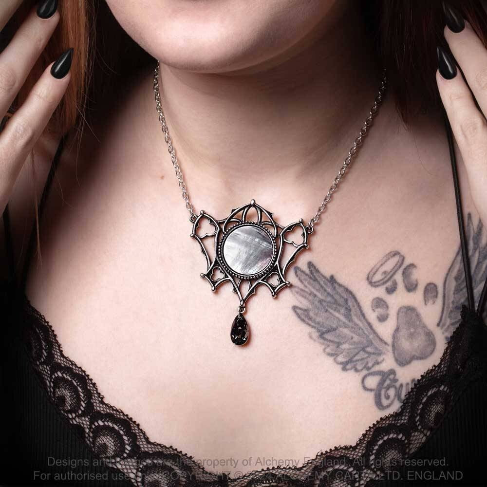 Necklace with a decorative pendant worn by a person with tattoos on their chest.