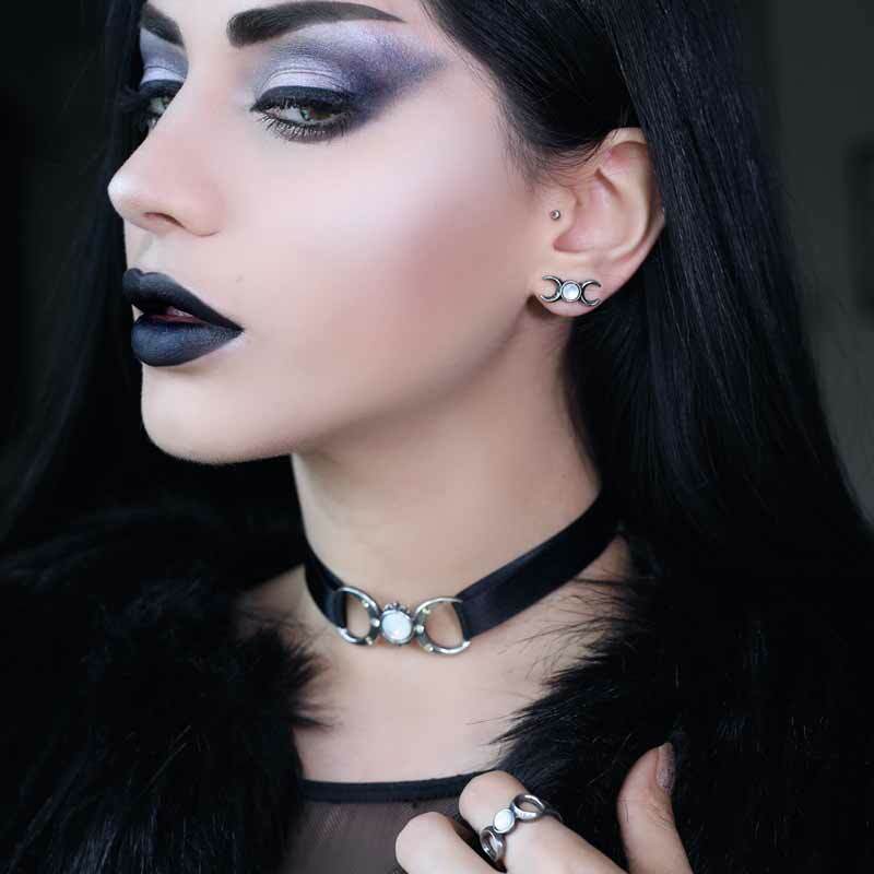 Close-up of a woman with dark makeup and black fur collar against a dark background