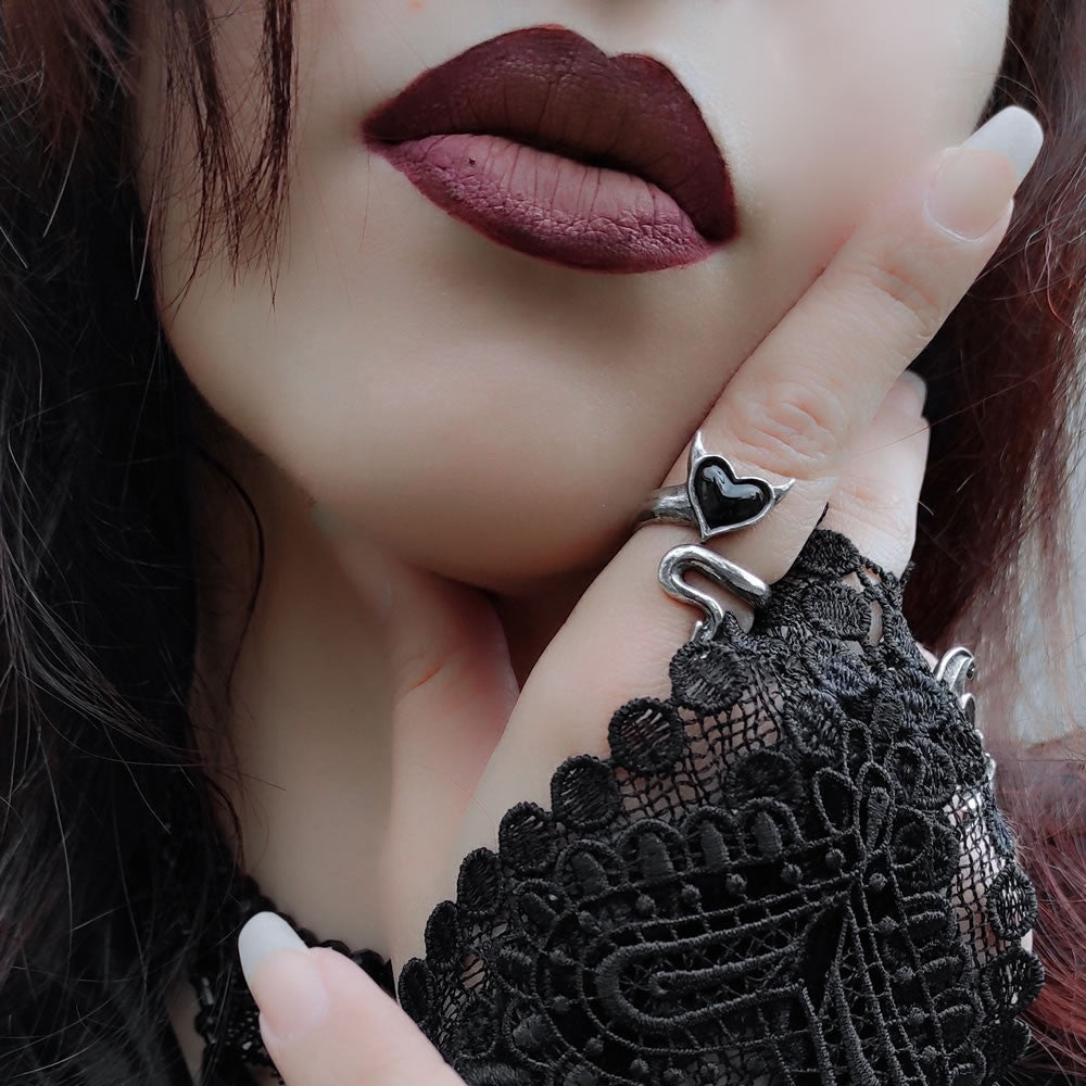 Close-up of a person wearing a black lace garment with a silver ring featuring a heart design.